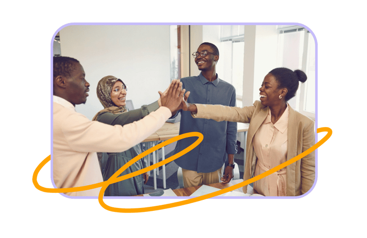 Four colleagues high-fiving in a circle at the office, visual for the article on workplace cohesion