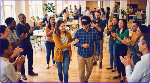 Exercice de sensibilisation en entreprise : une collaboratrice guide un collègue aux yeux bandés sous les applaudissements de l'équipe
